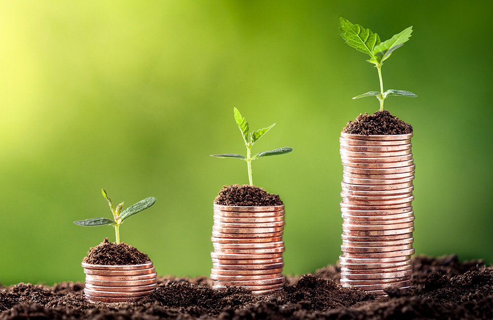 ESG investing concept illustrated by a row of stacked coins with seedlings growing from the top