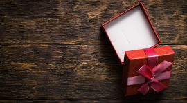 Une petite boîte cadeau ouverte sur une surface en bois.