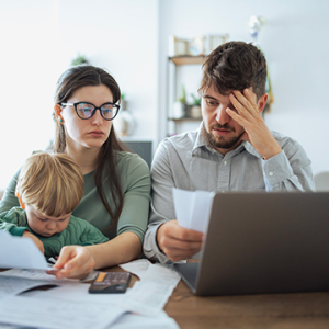 A worried couple with a toddler discuss their finances.
