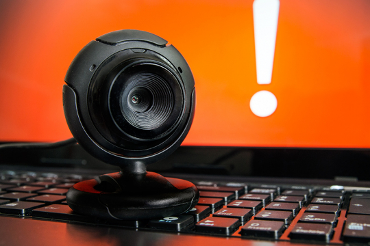 Web camera in front of a laptop showing an exclamation mark on the screen.