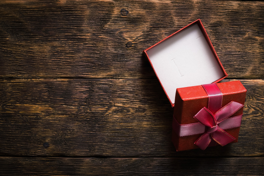 Small, open gift box on a wooden surface.