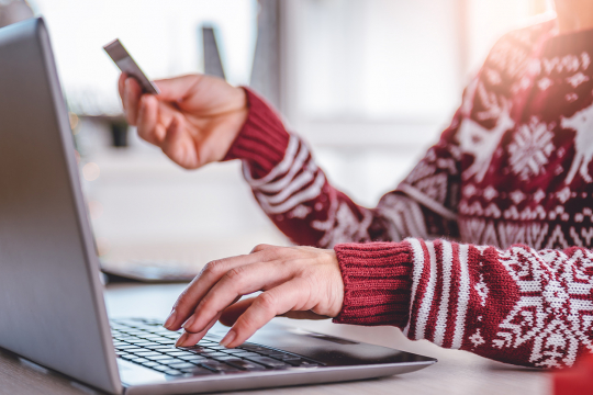 Une femme utilisant un ordinateur et tenant une carte de crédit.