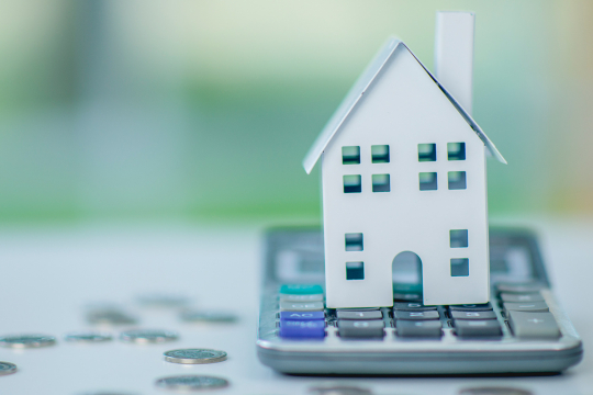 Une maquette en papier d'une maison placée sur une calculatrice.