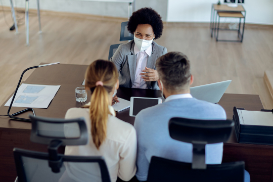 Un jeune couple rencontrant une femme d’affaires dans son bureau.