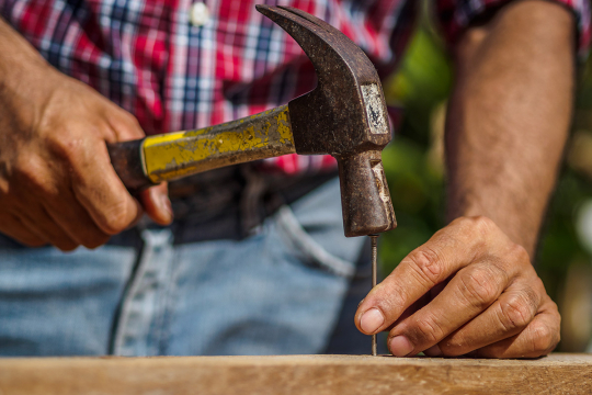 Un homme enfonçant un clou dans du bois