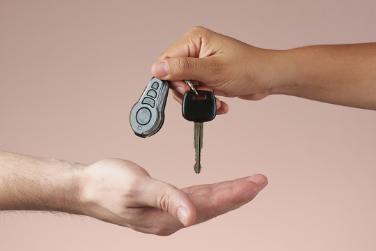 An adult dropping a car key into another person’s hand.