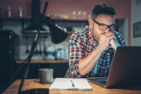 Young man in front of laptop considering an online payday loan