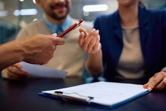 A couple preparing to sign a contract with a financial professional.