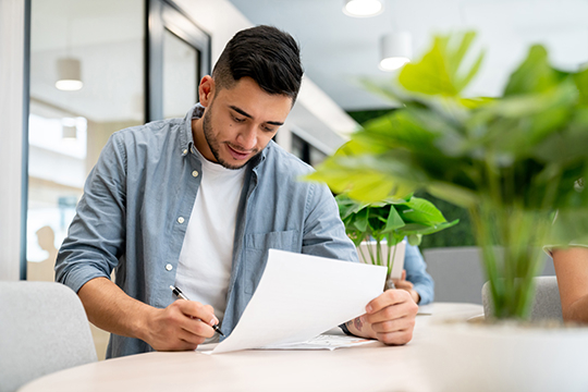 Man working at the office and reviewing and signing paperwork. 