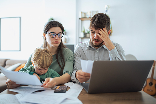 A worried couple with a toddler discuss their finances.