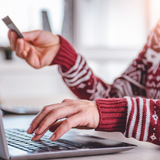 Une femme utilisant un ordinateur et tenant une carte de crédit.