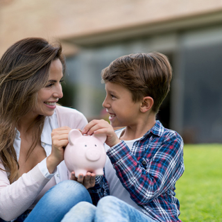 Une mère et son fils déposant des pièces de monnaie dans une tire-lire.