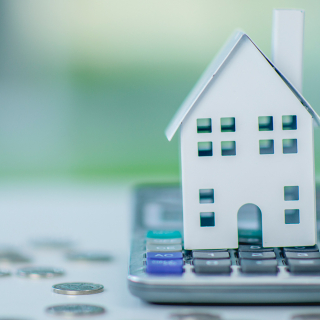 Une maquette en papier d'une maison placée sur une calculatrice.