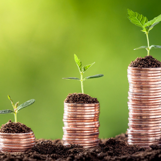 ESG investing concept illustrated by a row of stacked coins with seedlings growing from the top