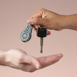An adult dropping a car key into another person’s hand.