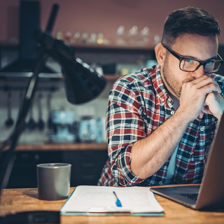 Young man in front of laptop considering an online payday loan